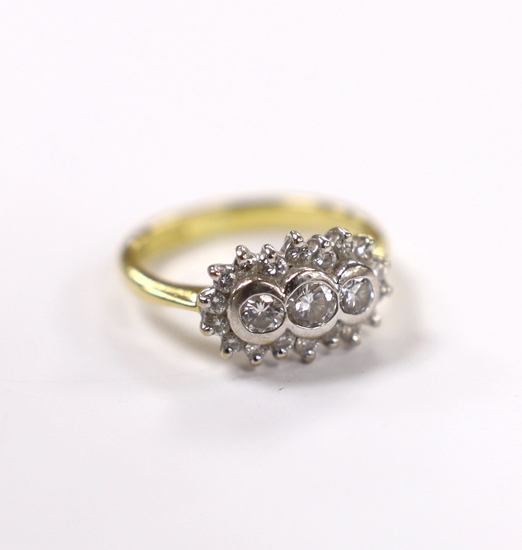 A modern 18ct gold and collet set three stone diamond ring, with diamond chip set border, size J/K, gross weight 4.6 grams.